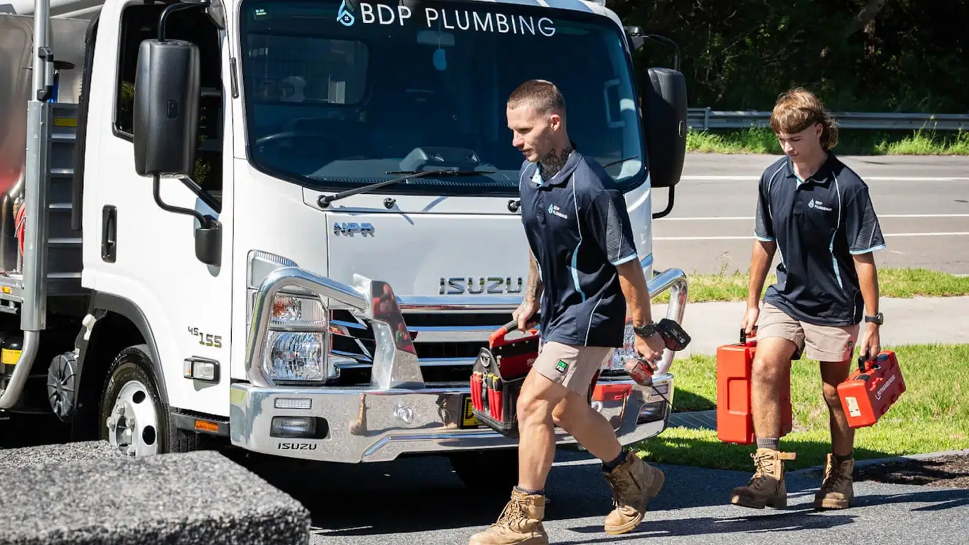 Two plumbers walking from the truck with tool cases